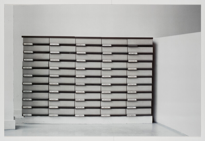 A wall of gray mailboxes with labeled slots arranged in neat rows and columns.