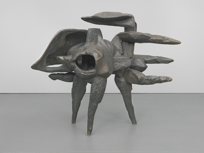 Bronze abstract sculpture resembling a multi-legged creature with layered, wing-like protrusions.