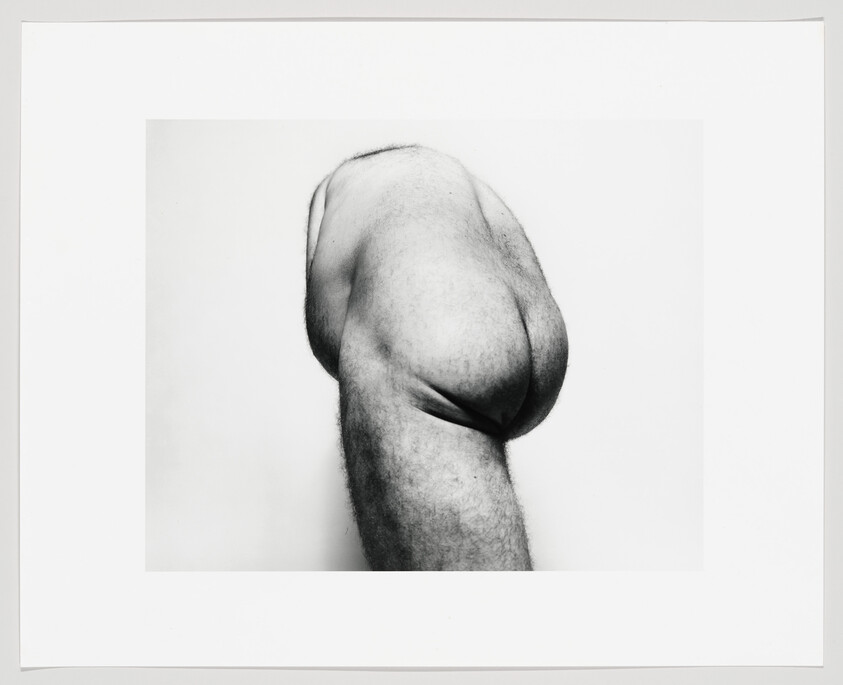 A white man's upper body is contorted, revealing his butt