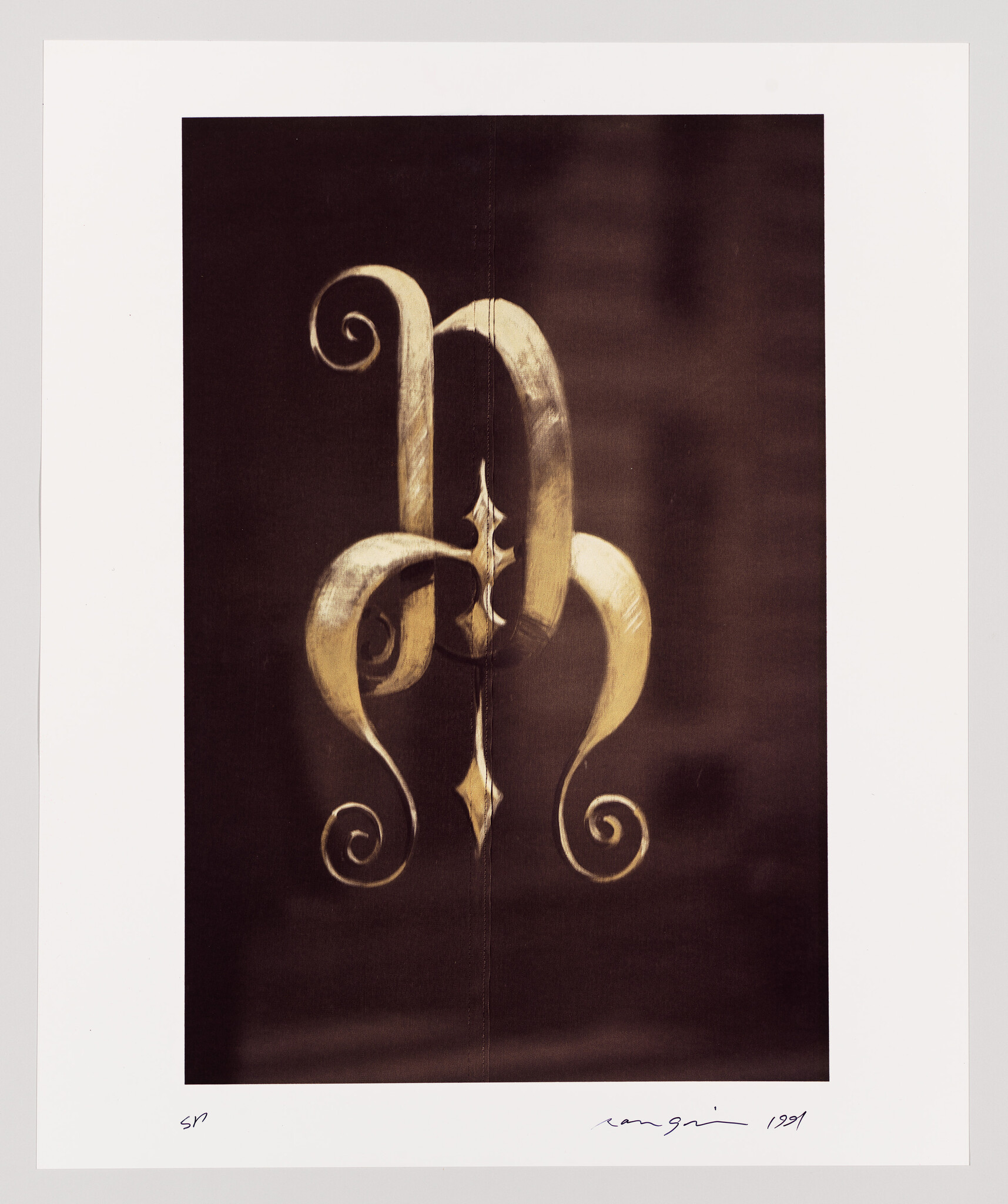 Ornate gold-colored wrought iron scrollwork with symmetrical curving shapes against a dark background.