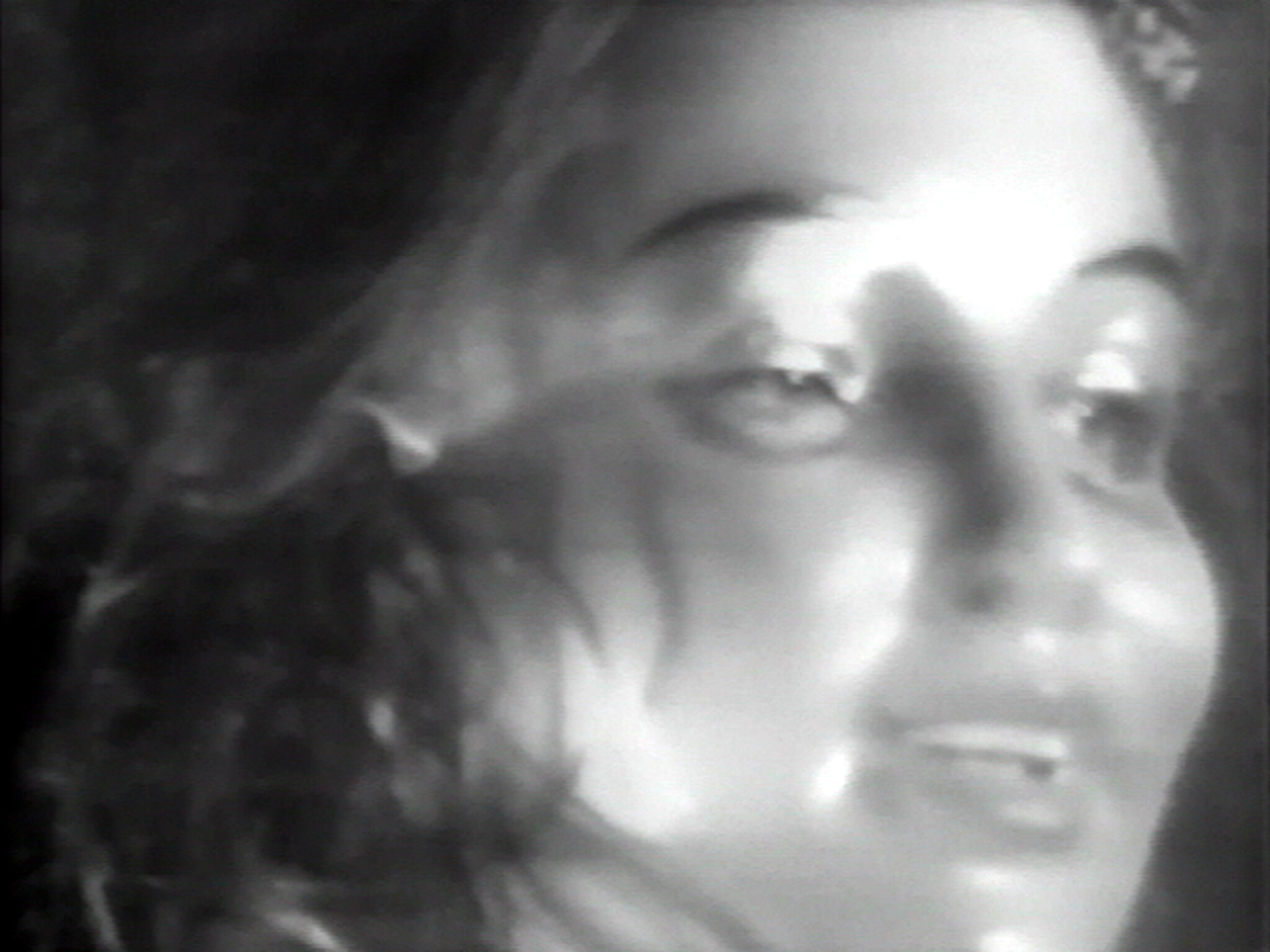 A woman’s face in close-up, shown in black and white, with a soft and slightly blurred focus.
