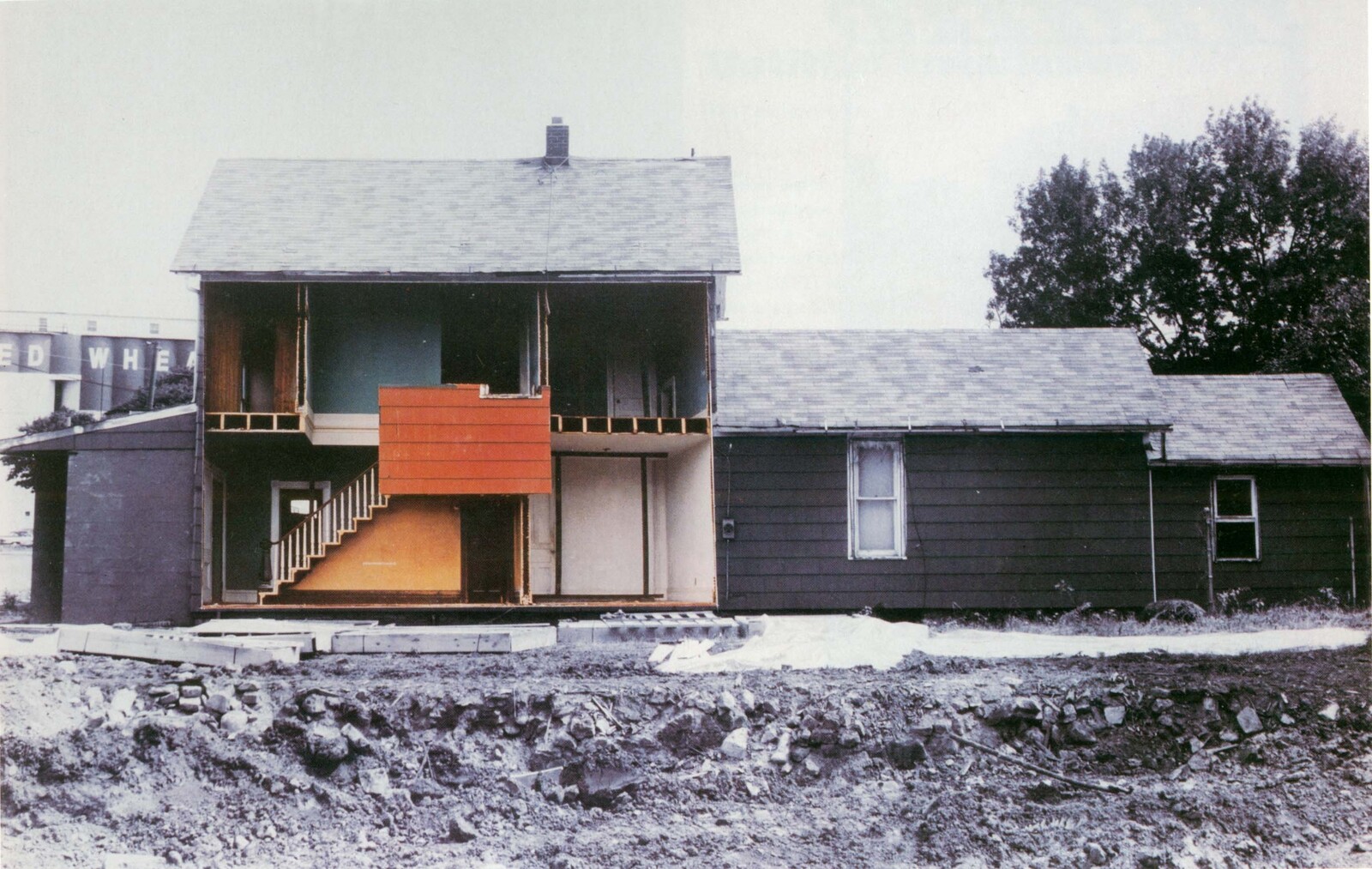 Partially demolished two-story house with exposed interior walls and a staircase visible to the street.