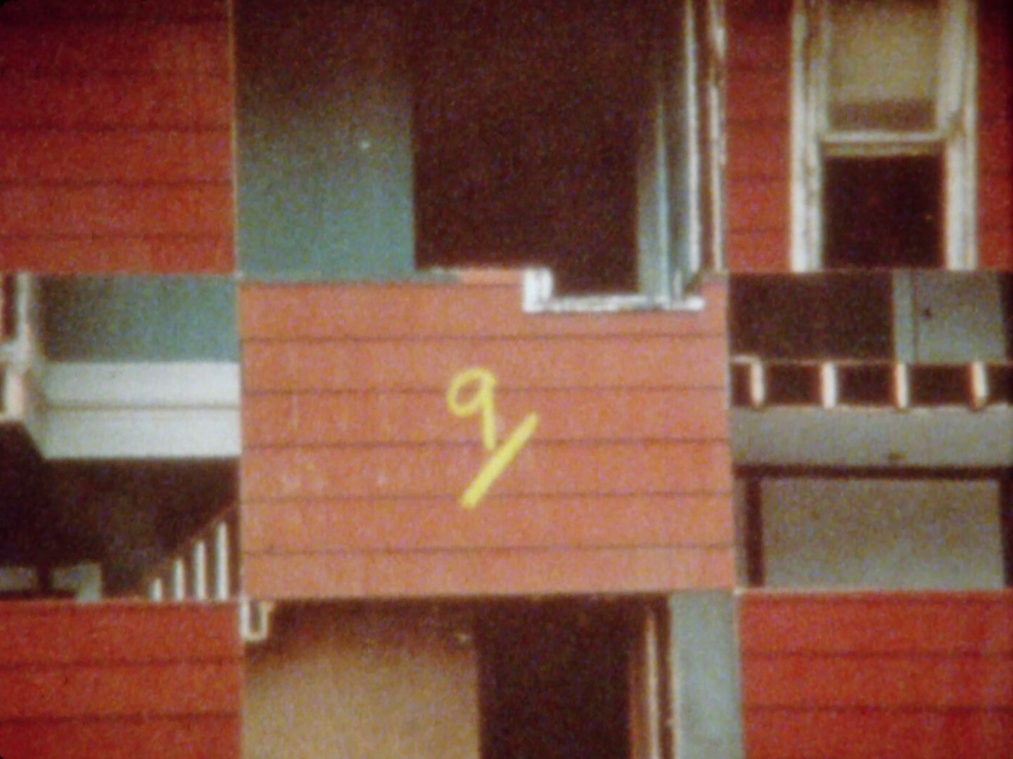 Partially demolished two-story house with exposed rooms and staircase on a cleared construction site.