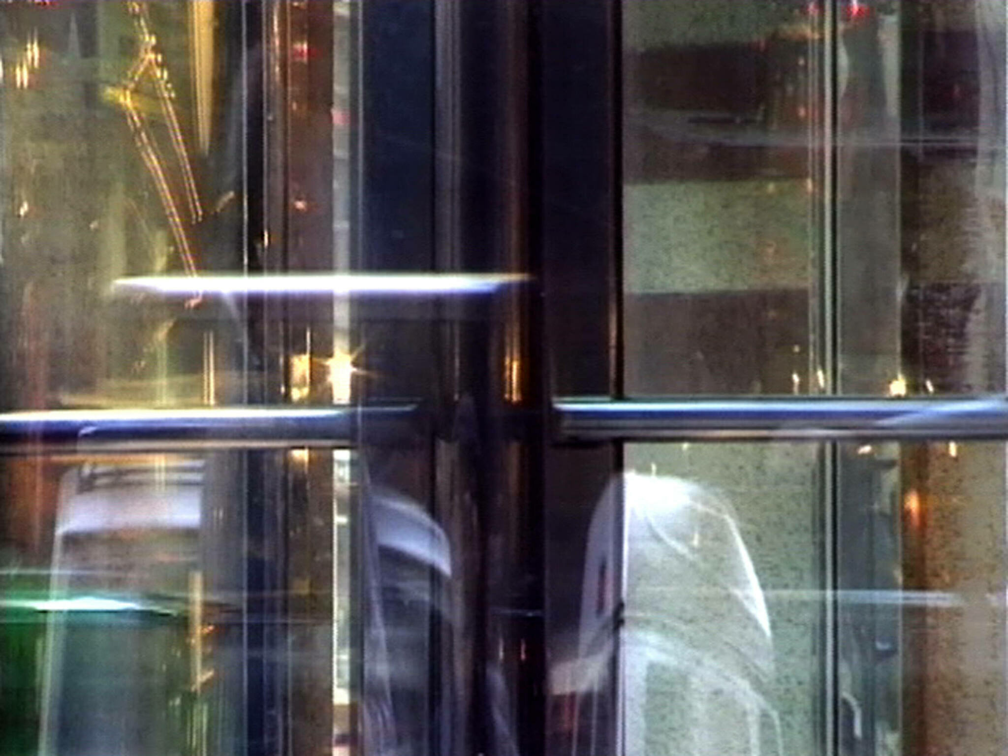 A blurred image of a revolving door with reflections and light streaks creating an abstract effect.