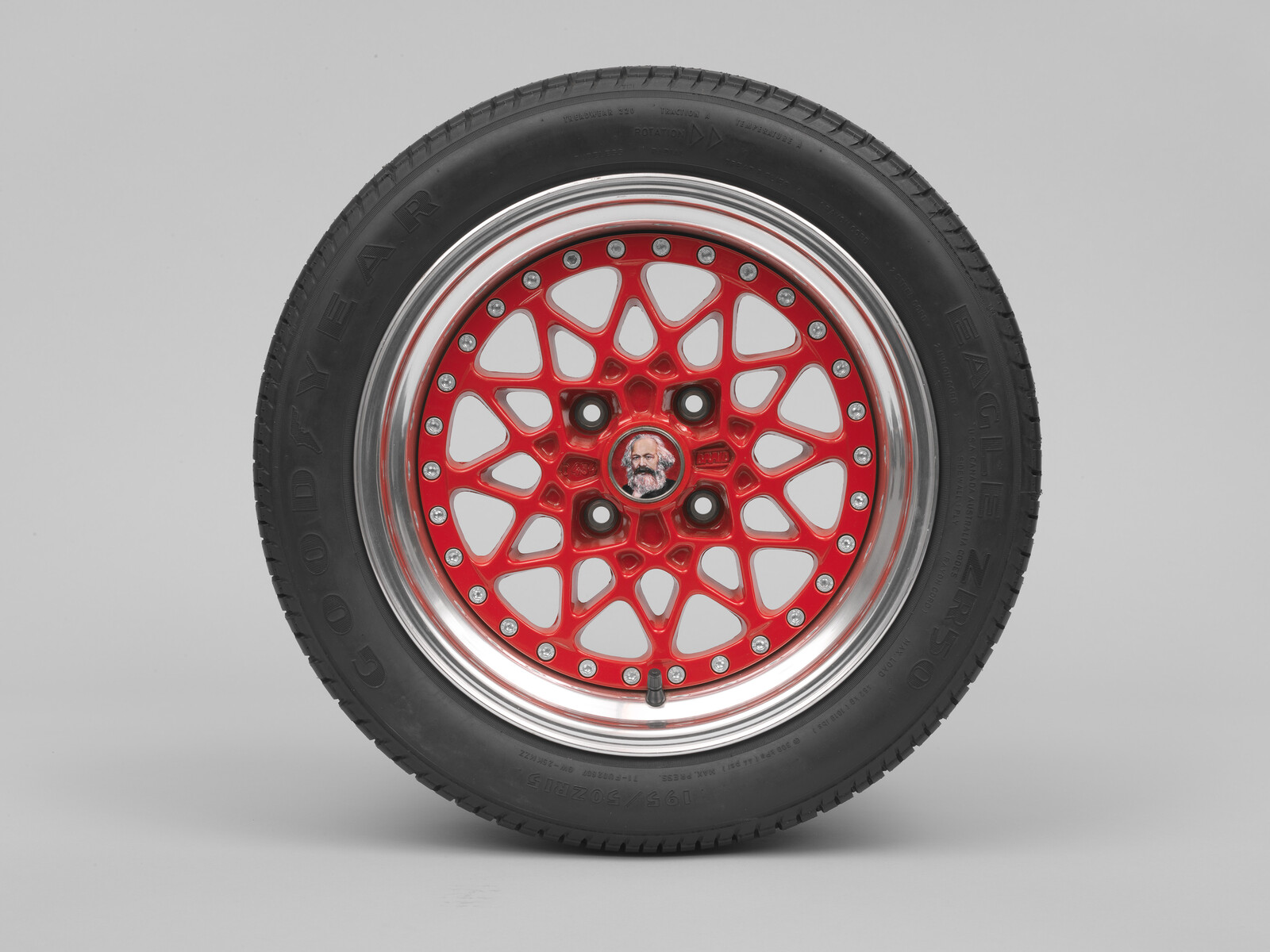 Black Goodyear tire mounted on a polished rim with red multi-spoke alloy wheel.