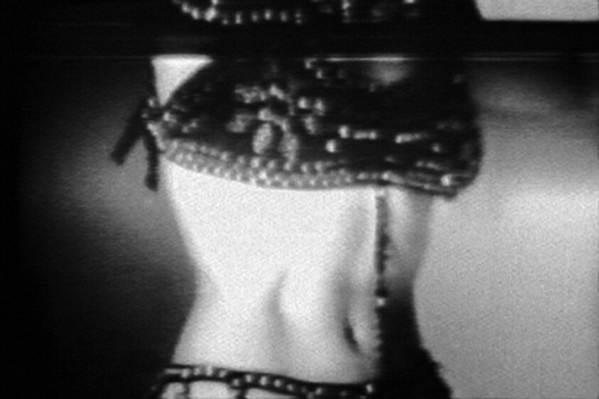 Black and white photo of a reflection of a woman's midsection wearing a decorative belt.