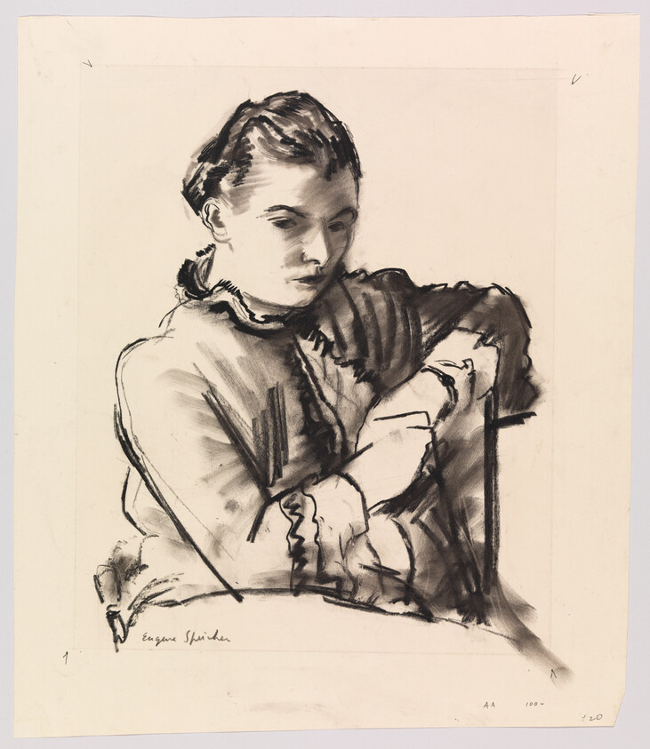 Young woman in a ruffled blouse sits with folded arms and a pensive expression.