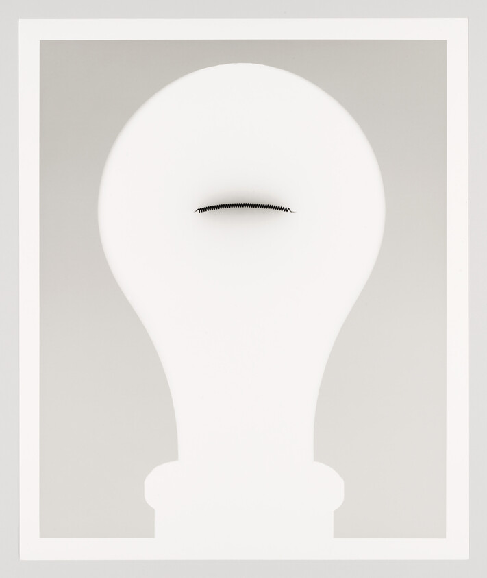 Large white light bulb silhouette with a small black zipper-like slit near the top center.