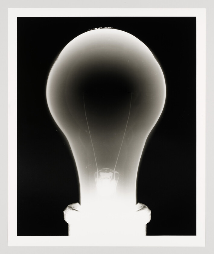 A glowing light bulb with visible filament and dark background.