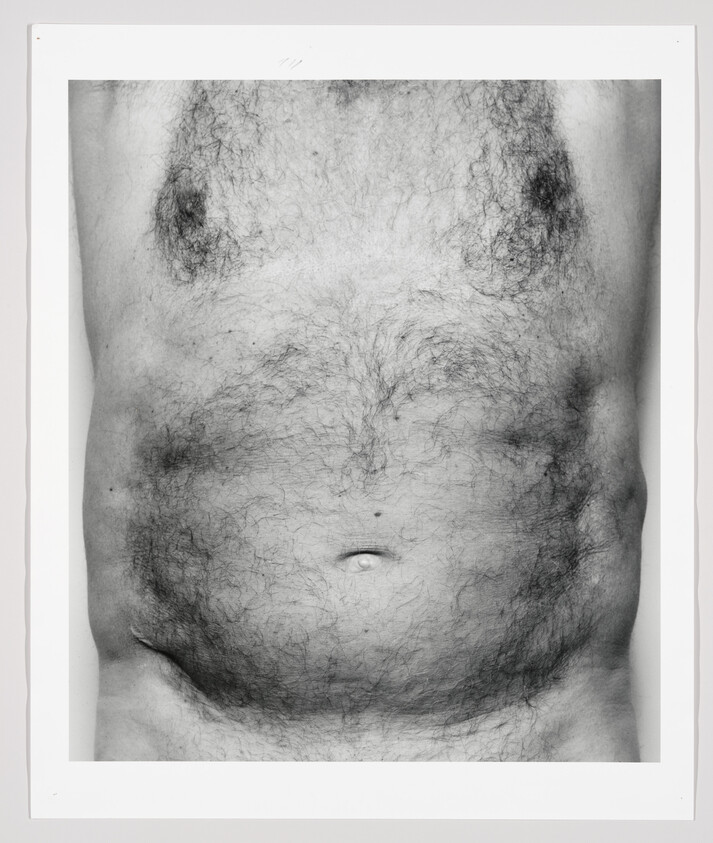 A black and white photograph of a man's hairy torso