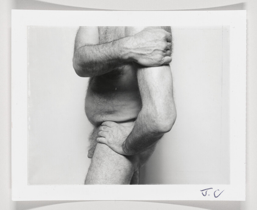 Naked torso and arms of a man with hands gripping his own upper arm and thigh.