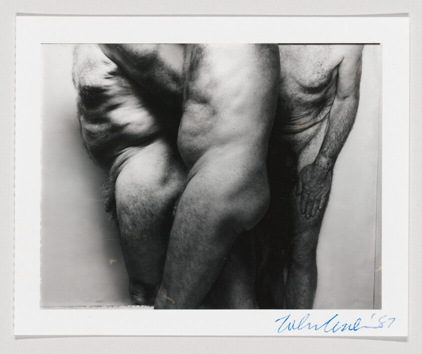 Three nude adult bodies closely grouped, showing torsos and legs in a black-and-white photograph.