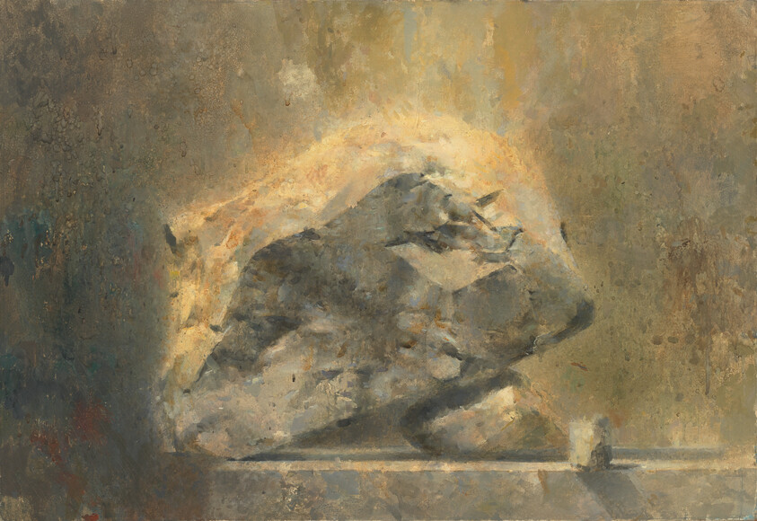 A large rough stone rests on a ledge with warm light glowing behind it.