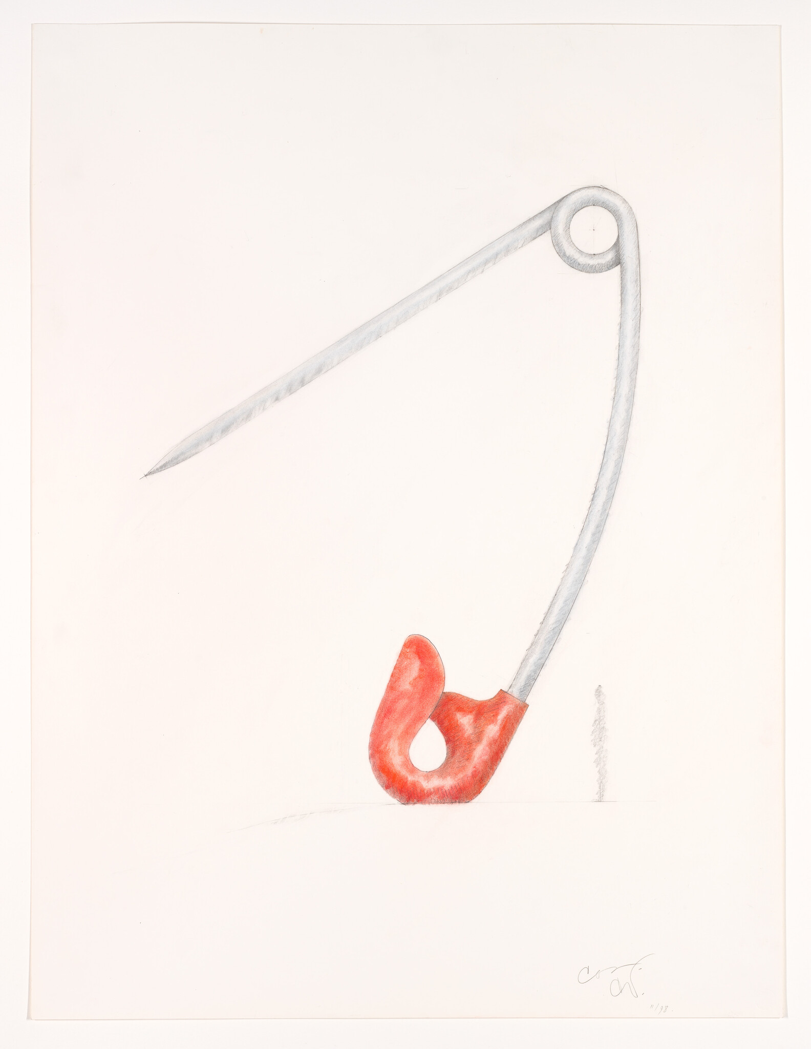 A large open safety pin with a red clasp leaning and touching a flat surface.