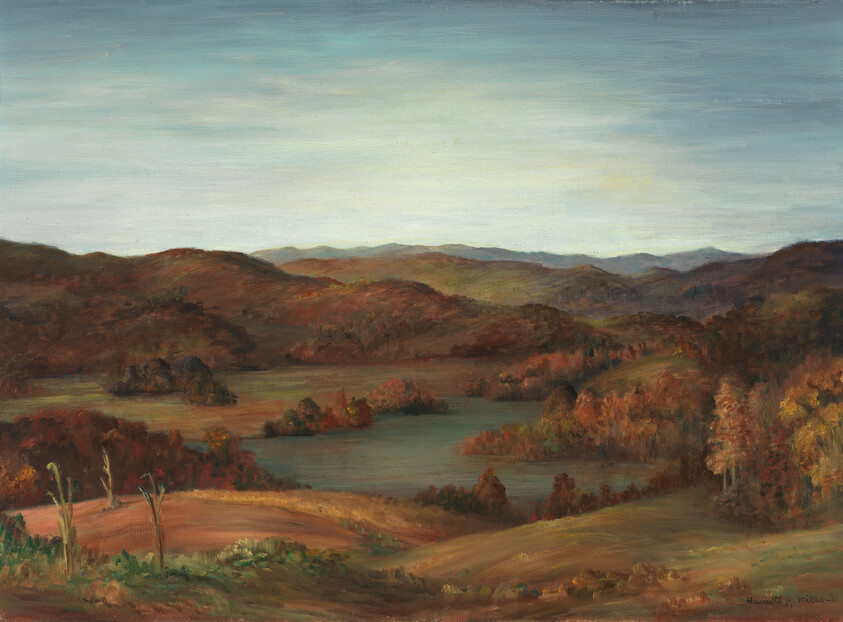 Rolling hills and lakes stretch under a pale sky, with trees showing autumn colors.