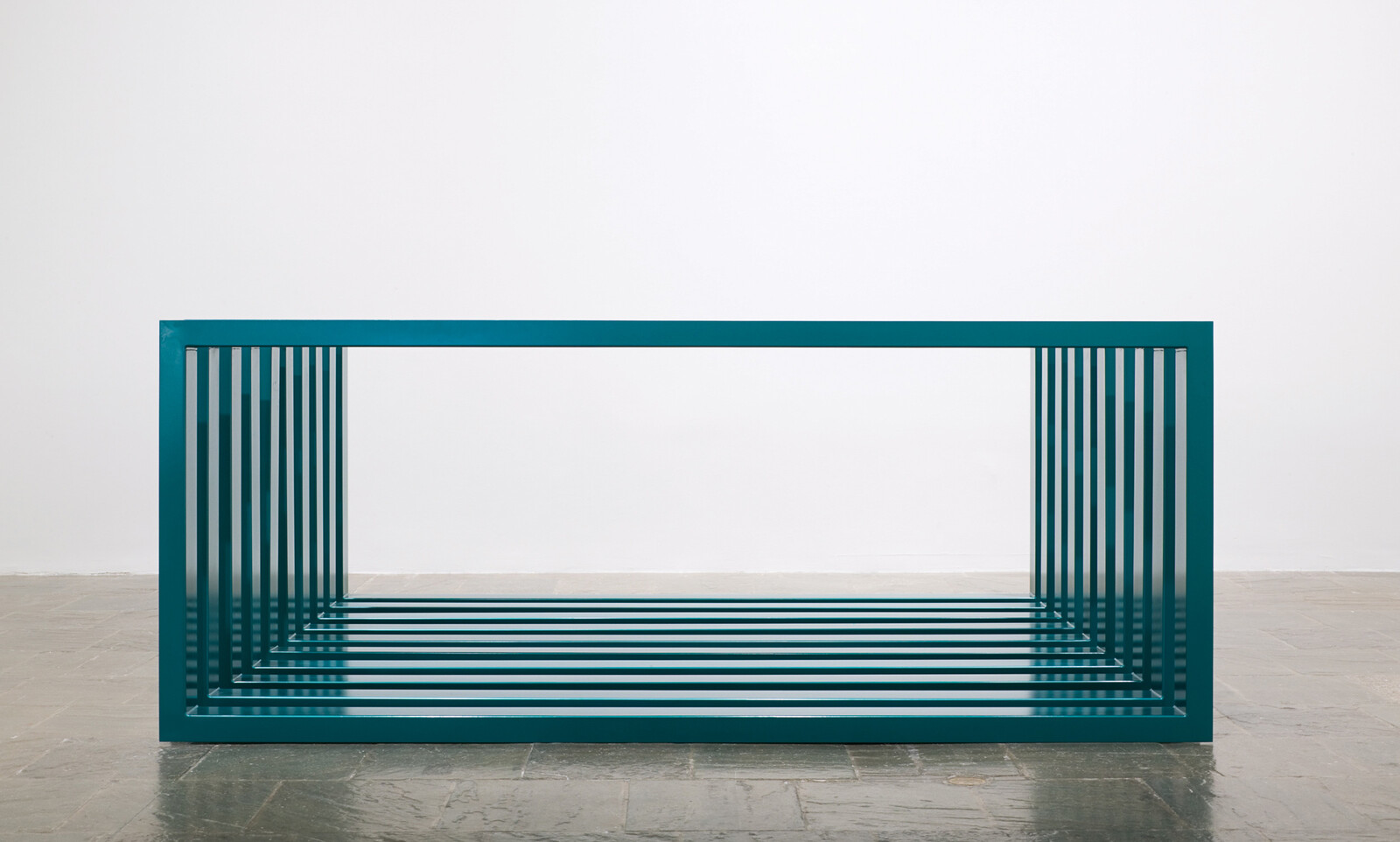 A teal rectangular metal frame with parallel slats forming a hollow box on the floor.