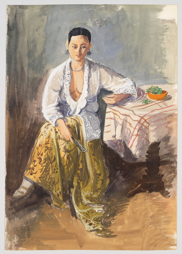 A seated woman in a white blouse and patterned skirt holds a fan while resting her arm on a table.