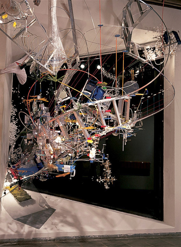 A suspended cloud of mirrors, plastic spoons, ladders, and other miscellaneous items chaotically interconnected
