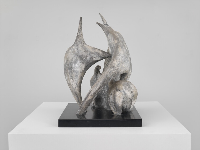 Abstract bronze sculpture of three stylized bird-like figures interacting on a black display base.