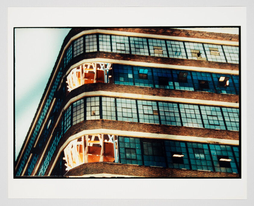 Curved brick office building corner with large grid windows and exposed orange construction scaffolding.