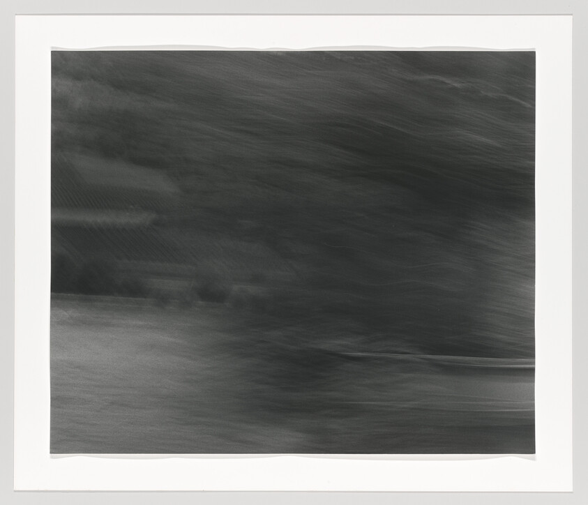 Dark blurred horizontal streaks suggesting moving water or a wind-blurred landscape.