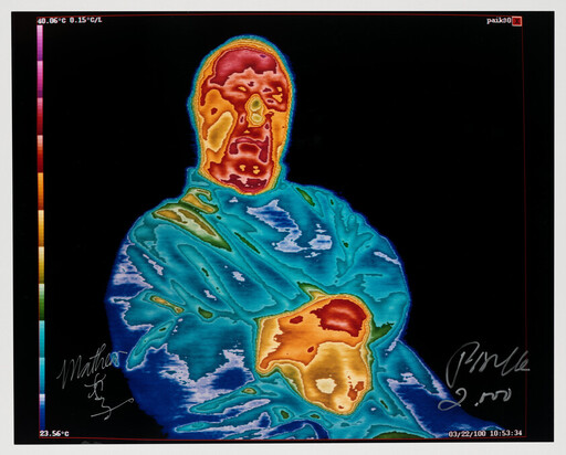 Person shown in thermal colors with a warm face and hands holding a warm object against their chest.