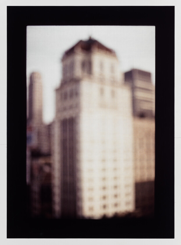 Tall blurred city building framed by a dark rectangular border, seen from a distance.