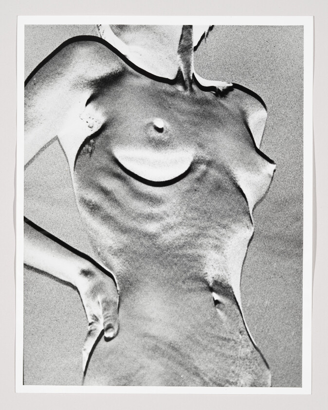 Nude female torso photographed from chest to hips with hand resting on hip, high-contrast black and white.