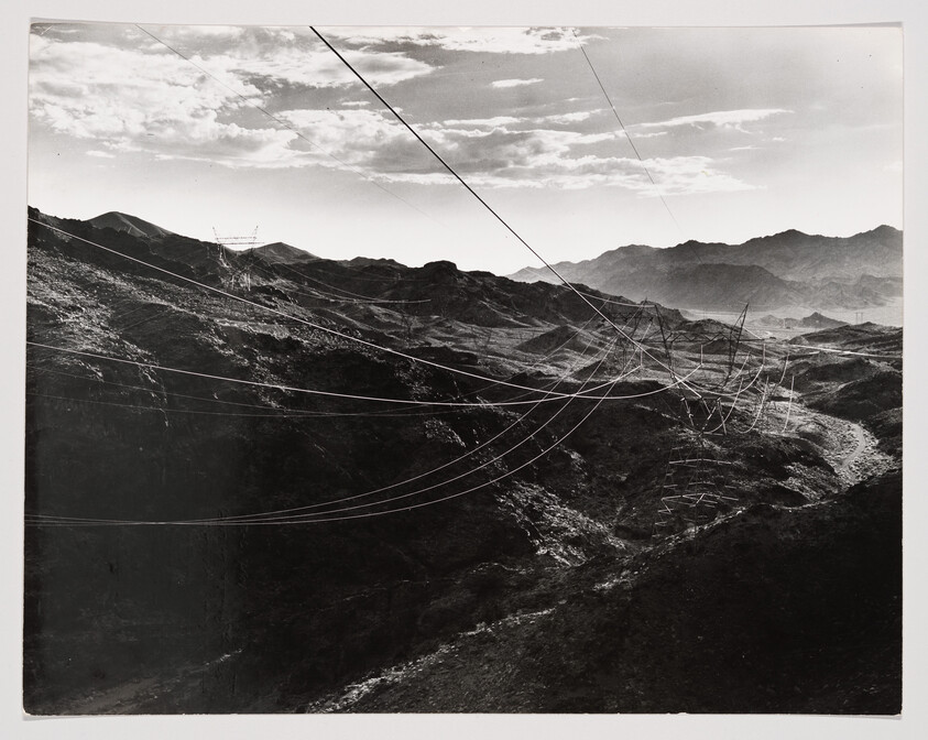 Power lines and transmission towers stretch across rugged mountains under a cloudy sky.