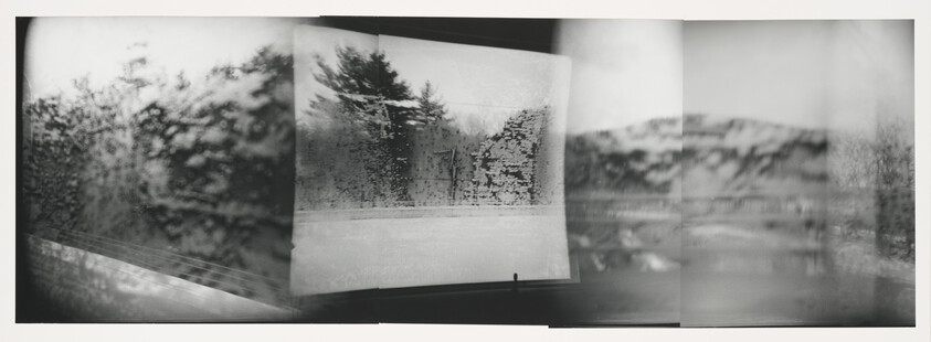Blurred black-and-white panorama of a rainy window showing trees and a shoreline beyond.