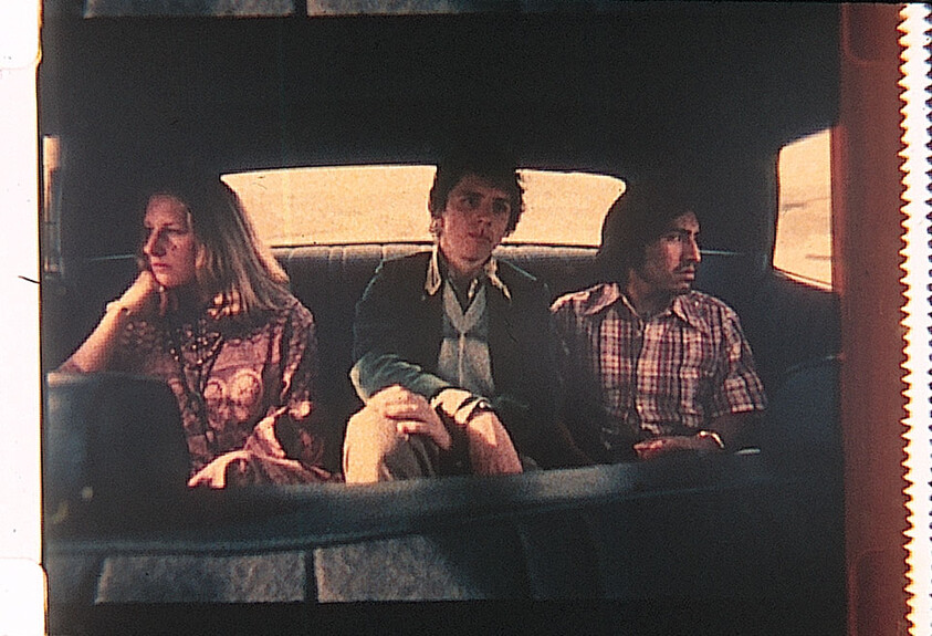 Three people sit quietly in the back seat of a car, each looking in a different direction.