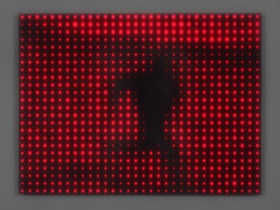 Silhouette of a person standing against a glowing red LED dot matrix panel.