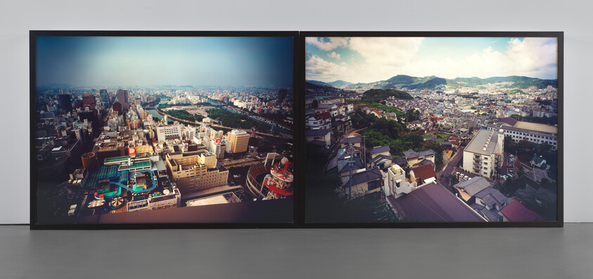 Two large framed aerial cityscape photographs showing dense urban buildings and distant hills.
