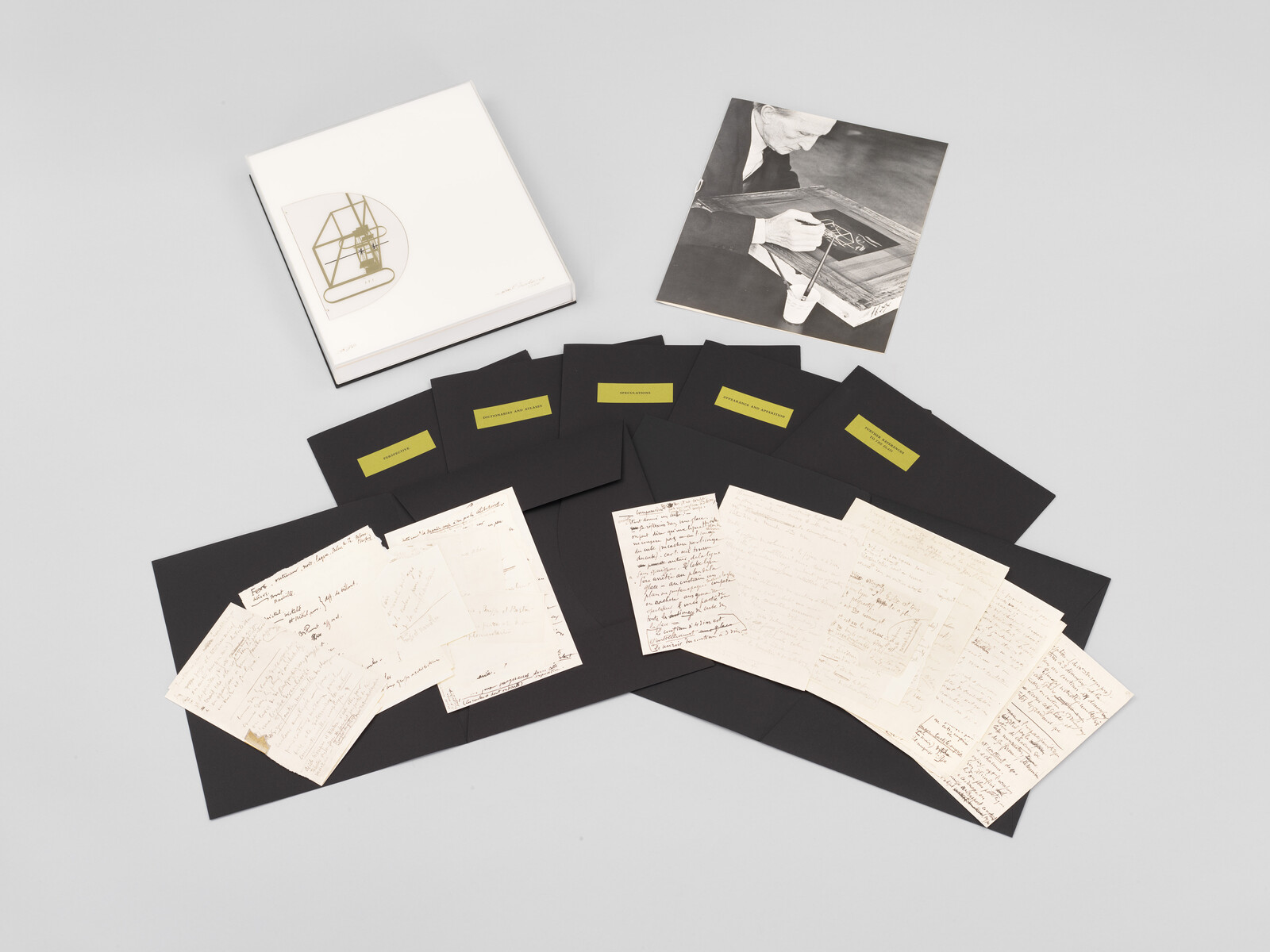 A spread of handwritten letters and black archival folders with a white storage box and photograph.