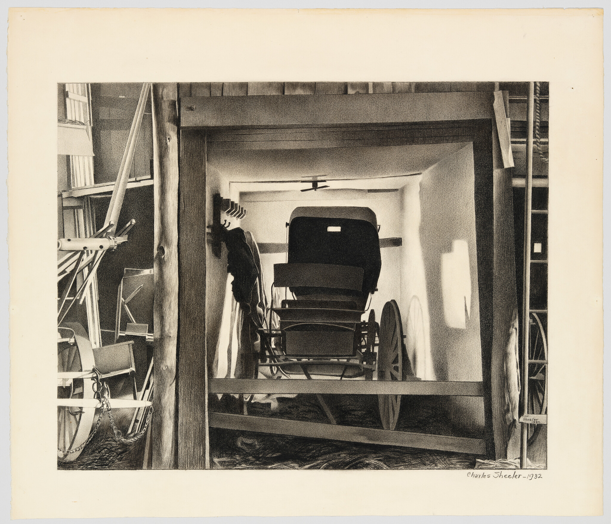 A vintage horse-drawn carriage sits stored inside a wooden barn framed by beams and shadows.