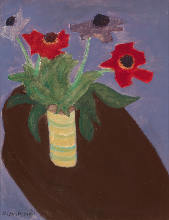 Bright red poppy-like flowers and green leaves in a striped yellow vase on a dark table.