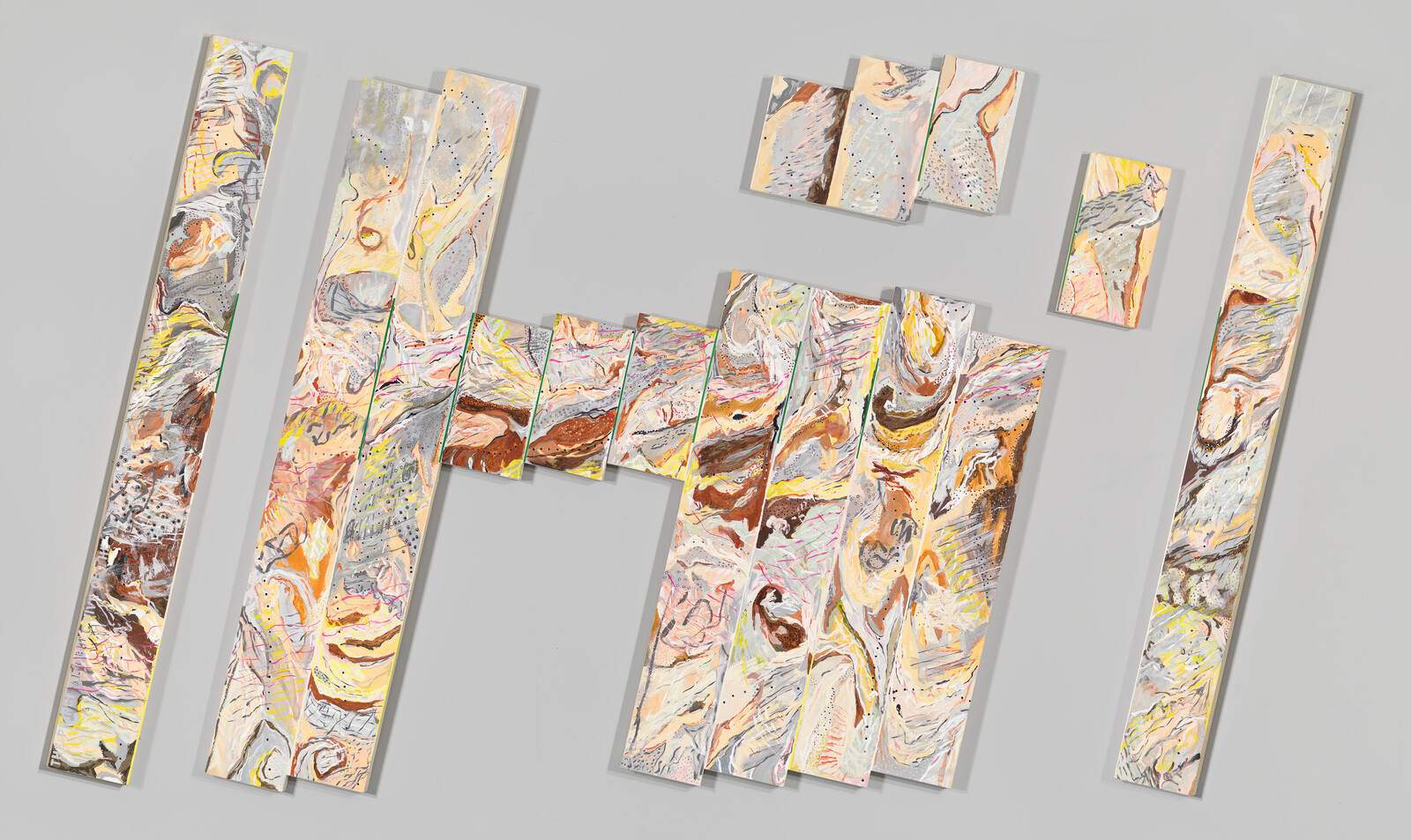 Several long, narrow abstract painted panels with swirling pastel colors arranged on a gray wall.