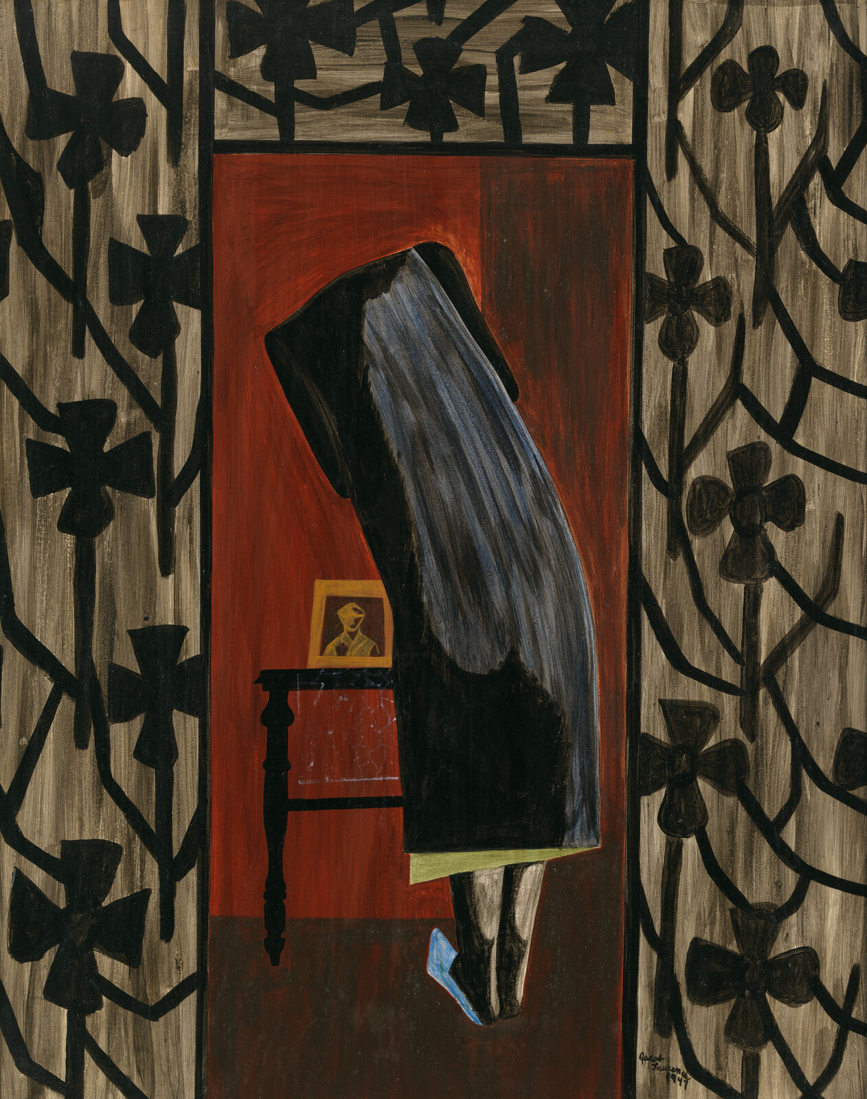 Person in a dark cloak leans over a table with a framed photo, surrounded by floral patterns.