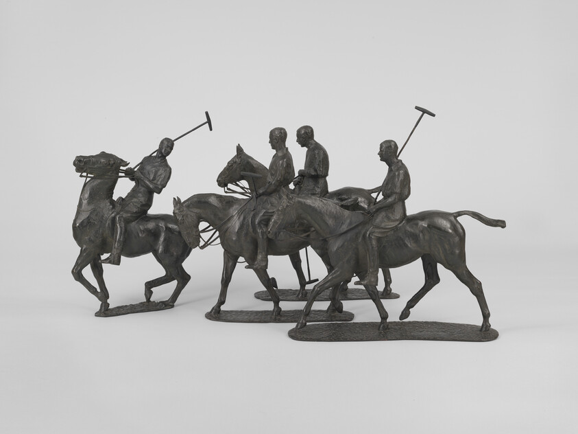 Four bronze polo players ride horses holding mallets in a small sculptural group.