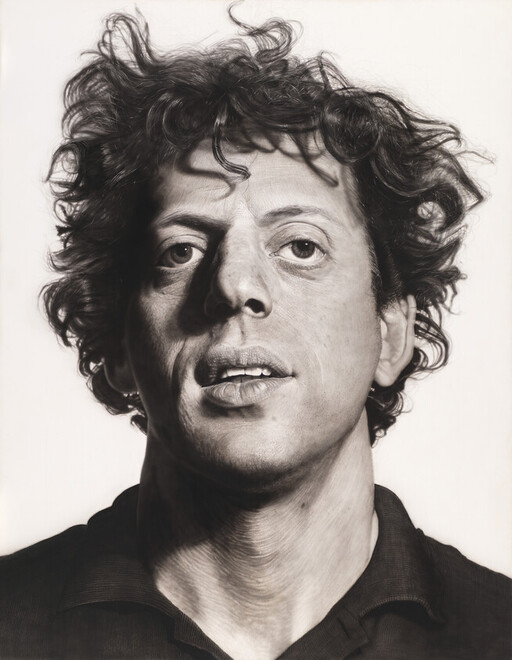 A man with messy curly hair looks slightly upward with a neutral expression.