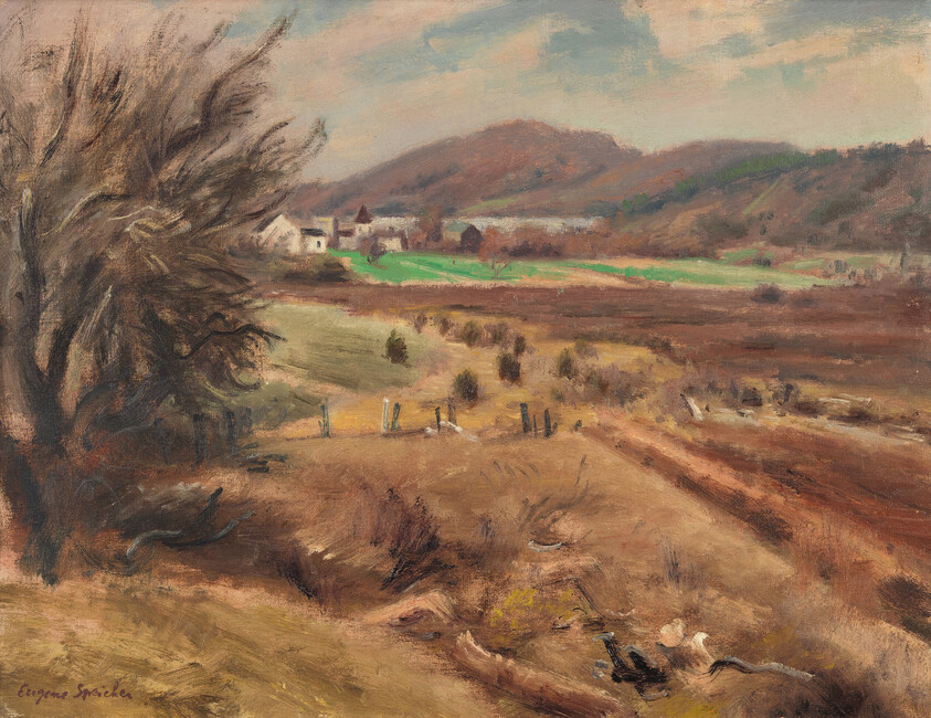 A windswept autumn landscape with a large bare tree, brown fields, and distant houses by hills.