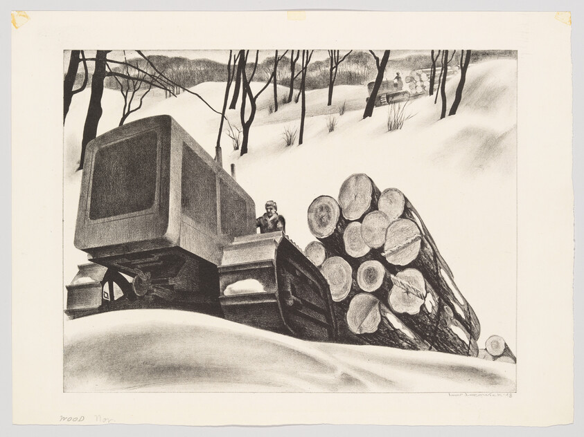 Tracked tractor pushes large cut logs through deep snow with driver visible in cab.