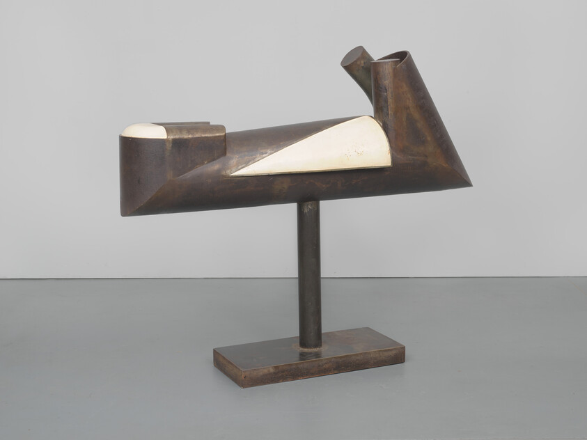 Bronze abstract geometric sculpture with white triangular inlay mounted on a central pedestal.