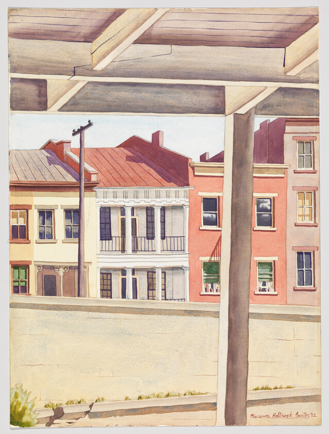 View of three colorful row houses seen from behind a concrete wall under porch beams.