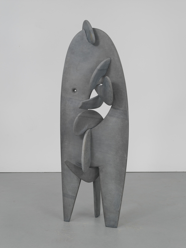 Tall freestanding sculpture made of organically-shaped, interlocking slabs of grey stone