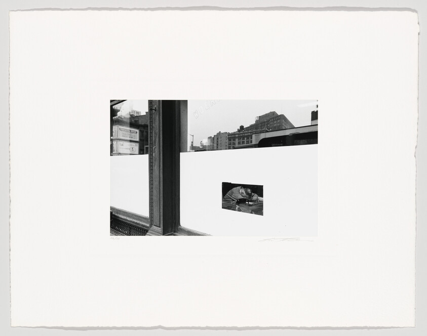 A black and white photograph featuring a collage of images. On the left, a window frame reveals a blurred cityscape with buildings and a sign that reads "WORK." On the right, a smaller, clear image of a man working on a boat is inset against a white background. The overall composition is bordered by the rough edges of the photo paper, and there are artist's signatures at the bottom.