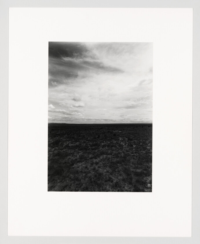 A vast flat plain under a wide cloudy sky in black-and-white.