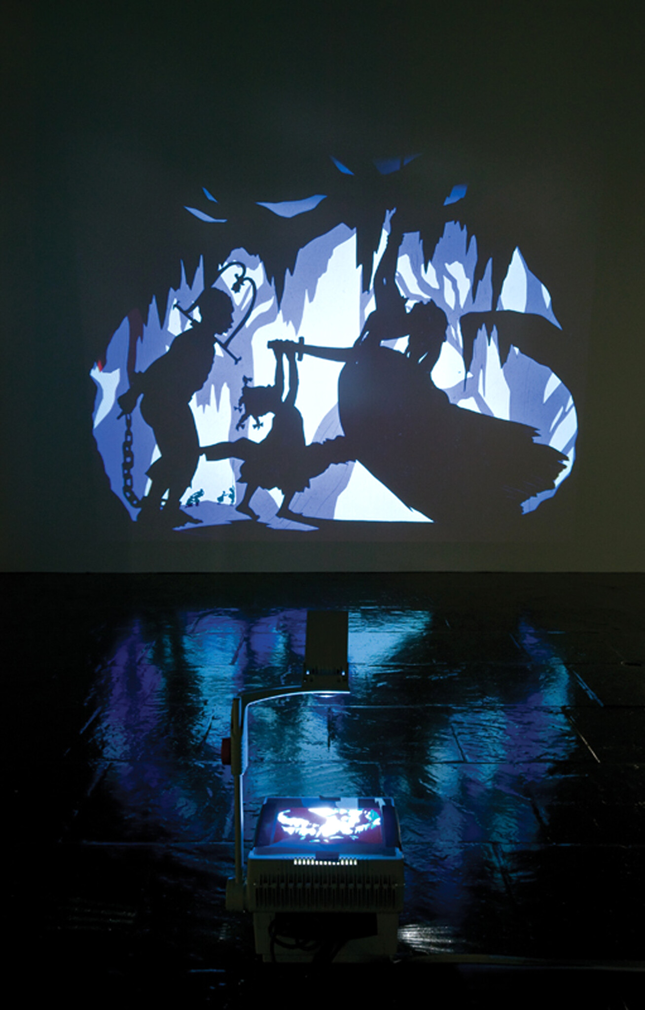 An overhead projector casts a blue silhouette scene of three figures struggling in a cave.