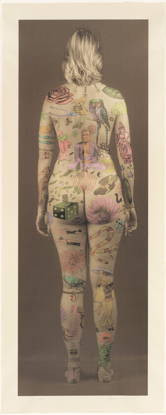 Naked woman seen from behind with numerous colorful tattoos and drawings covering her back and legs.