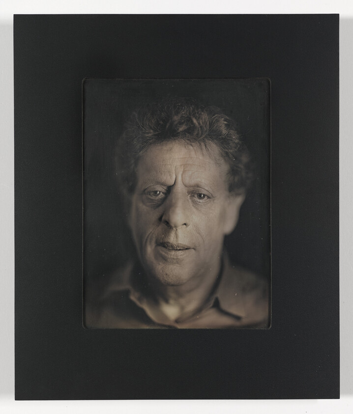 A monochromatic portrait of a middle-aged man with tousled hair, centered on a black background. The man's expression is serious and contemplative, with his gaze directed slightly off-camera. The image has a vintage feel, possibly created using a traditional photographic process, and is framed within a dark border, giving it a classic, timeless quality.